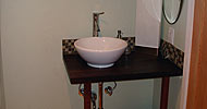 Mahogany slab vanity with vessel style sink and glass tile backsplash. Created for Lynn MacKeller basement remodel.